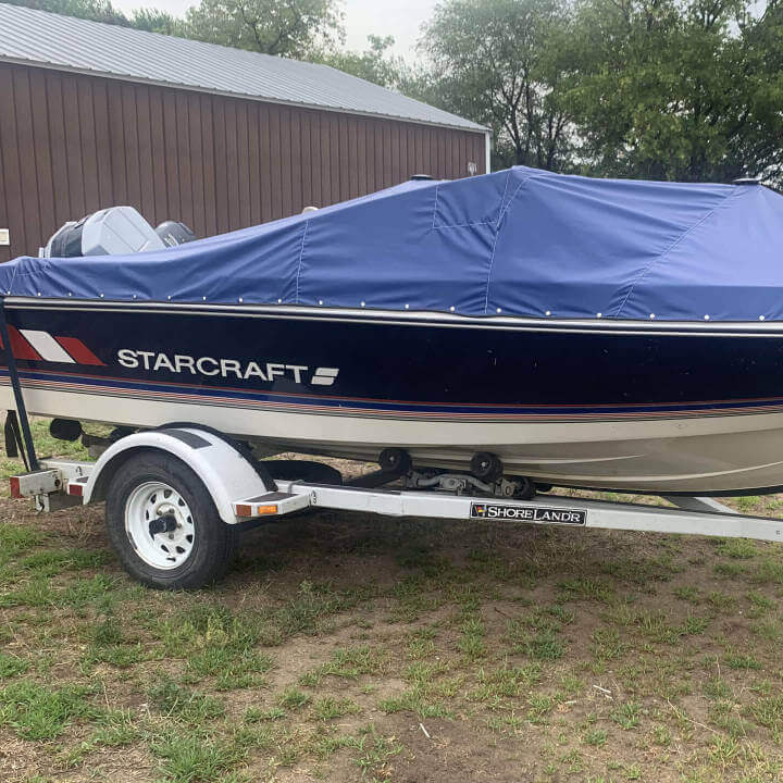 Boat on a trailer with a dark blue cover