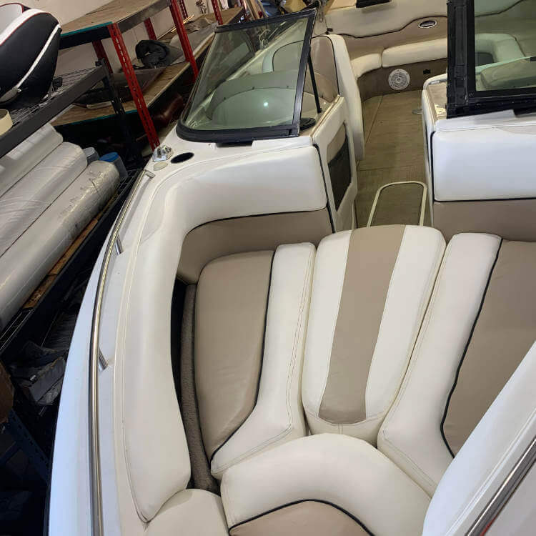 The front of a boat with white and tan vinyl seats